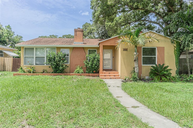 single story home featuring stucco siding, a front yard, and fence