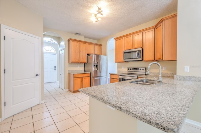 kitchen featuring visible vents, appliances with stainless steel finishes, a peninsula, arched walkways, and a sink