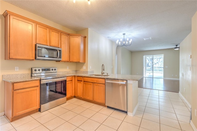 kitchen with a peninsula, an inviting chandelier, a sink, stainless steel appliances, and open floor plan