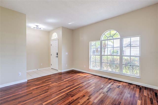 empty room with wood finished floors, baseboards, and a textured ceiling