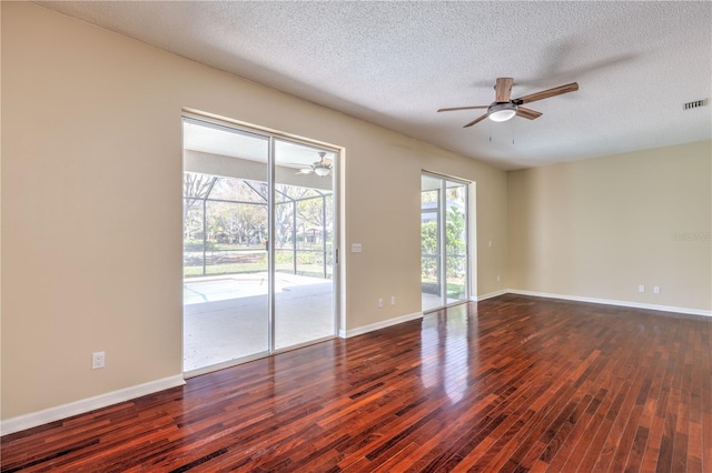 unfurnished room with baseboards, dark wood-style floors, visible vents, and ceiling fan