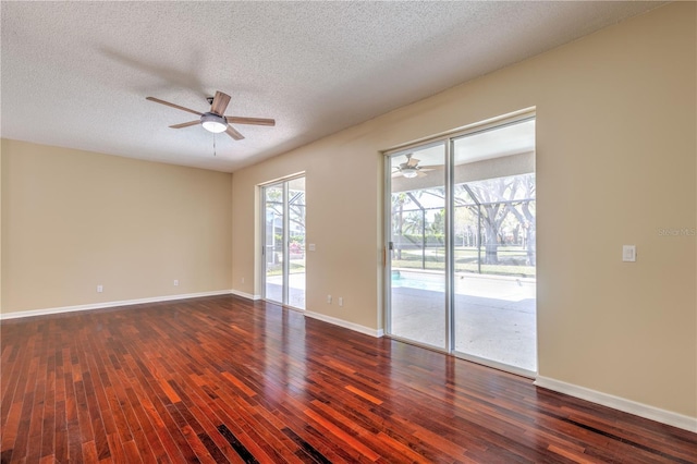 spare room with dark wood-style floors, a ceiling fan, baseboards, and a textured ceiling