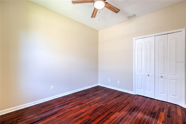 unfurnished bedroom featuring dark wood-type flooring, visible vents, baseboards, and a closet