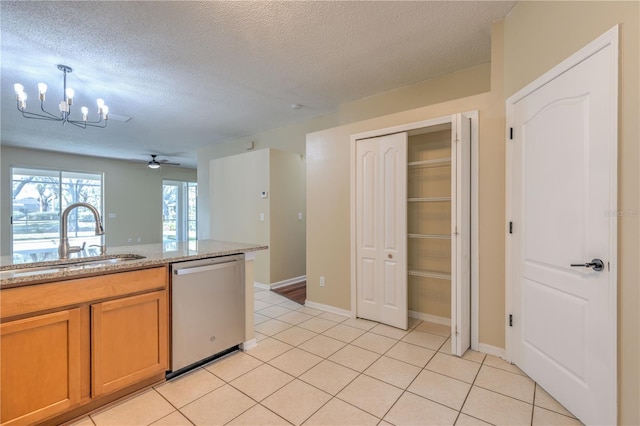 kitchen with light tile patterned floors, ceiling fan with notable chandelier, stainless steel dishwasher, a textured ceiling, and a sink