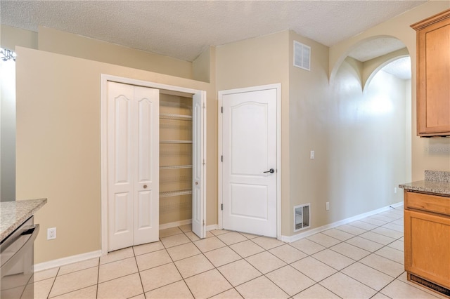 kitchen with light tile patterned floors, visible vents, arched walkways, and dishwasher