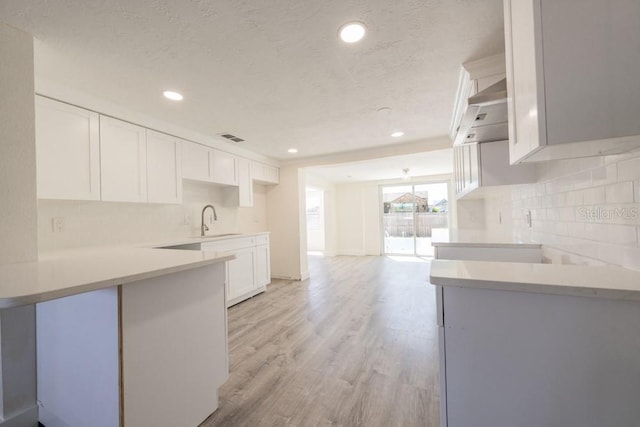 7322 Mako Dr, Hudson, FL 34667 - kitchen featuring white cabinetry, decorative backsplash, a sink, visible vents, and light wood-style flooring