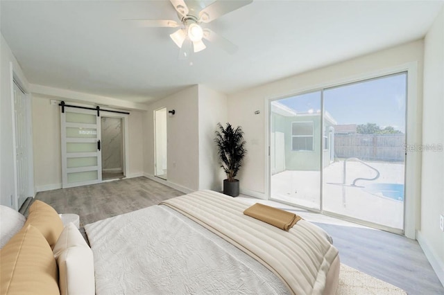 7322 Mako Dr, Hudson, FL 34667 - bedroom with baseboards, a barn door, access to exterior, ceiling fan, and wood finished floors