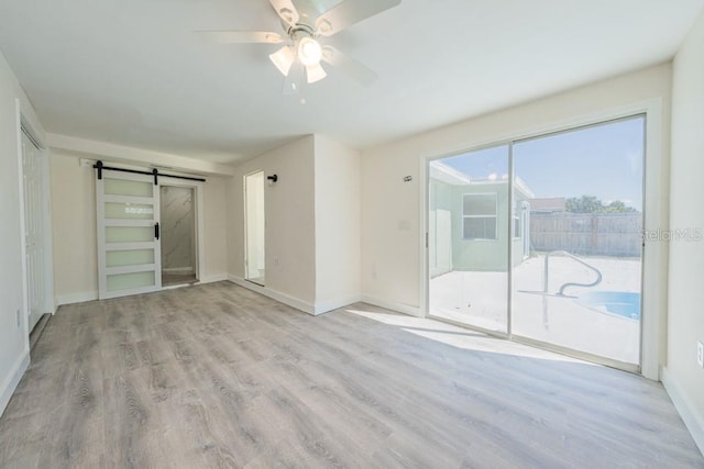 7322 Mako Dr, Hudson, FL 34667 - unfurnished room with baseboards, a barn door, ceiling fan, and wood finished floors
