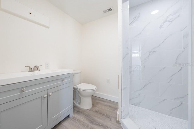 7322 Mako Dr, Hudson, FL 34667 - bathroom with baseboards, toilet, wood finished floors, vanity, and tiled shower