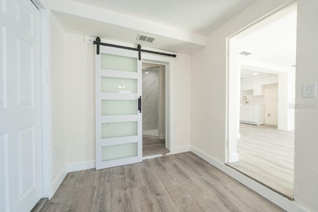 7322 Mako Dr, Hudson, FL 34667 - unfurnished room with light wood-style flooring, baseboards, a barn door, and visible vents