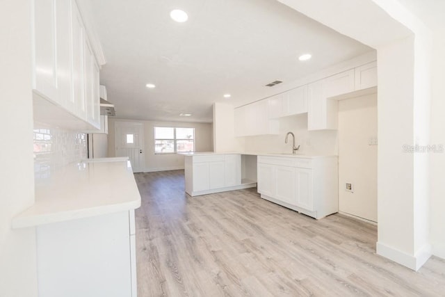 7322 Mako Dr, Hudson, FL 34667 - kitchen with visible vents, light wood-style flooring, a sink, and white cabinets