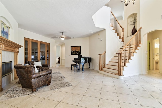 601 Viento De Avila, Tampa, FL 33613 - living area with a tile fireplace, ceiling fan, stairway, arched walkways, and light tile patterned floors