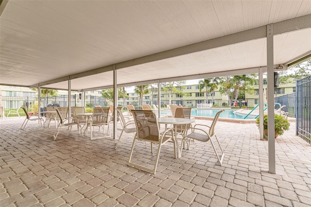 4885 1st St NE Unit 305, Saint Petersburg, FL 33703 - view of patio featuring a community pool, outdoor dining space, and fence
