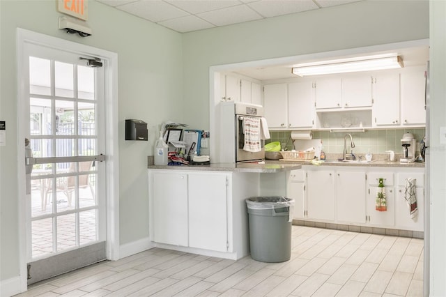 4885 1st St NE Unit 305, Saint Petersburg, FL 33703 - kitchen featuring open shelves, a sink, decorative backsplash, white cabinets, and a paneled ceiling