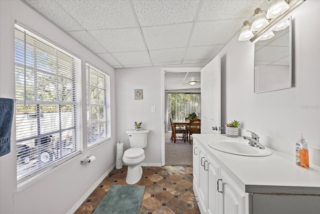 bathroom with vanity, toilet, a paneled ceiling, and a wealth of natural light