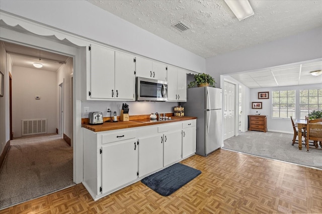 kitchen featuring white cabinetry, visible vents, appliances with stainless steel finishes, and wooden counters