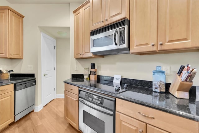 kitchen with dark stone countertops, light wood-style flooring, light brown cabinets, and appliances with stainless steel finishes