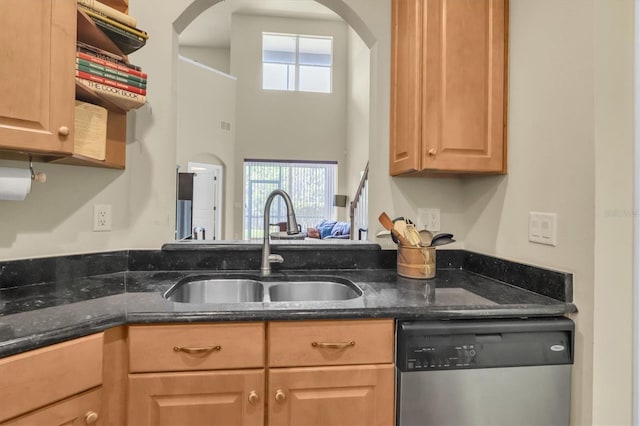 kitchen with arched walkways, dishwasher, dark stone counters, and a sink