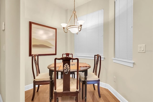 dining area with a notable chandelier, baseboards, and wood finished floors
