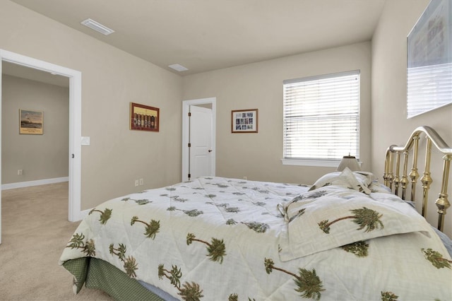 bedroom with baseboards, visible vents, and light carpet