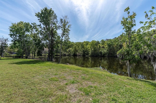 view of yard featuring a forest view and a water view
