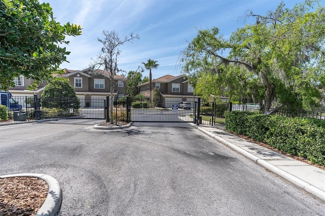 view of street with a gate, curbs, a residential view, and a gated entry