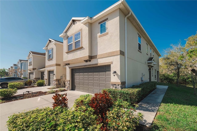 multi unit property with stone siding, stucco siding, an attached garage, and driveway