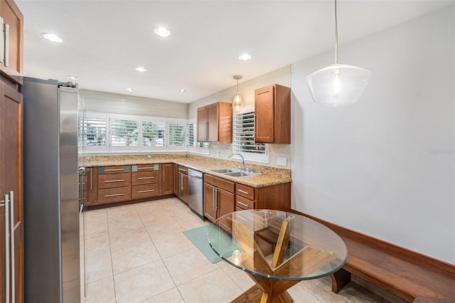 kitchen featuring brown cabinets, hanging light fixtures, appliances with stainless steel finishes, a sink, and recessed lighting