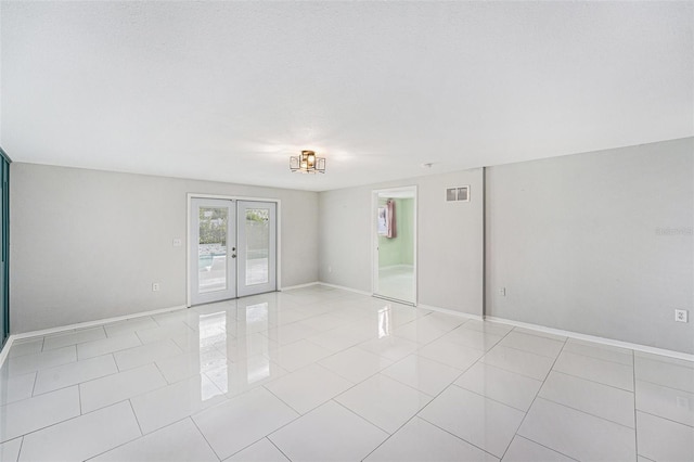 spare room with baseboards, french doors, light tile patterned flooring, and visible vents