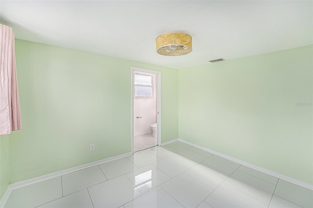empty room featuring baseboards, light tile patterned floors, and visible vents