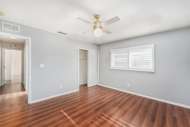 unfurnished bedroom with a closet, attic access, wood finished floors, and visible vents