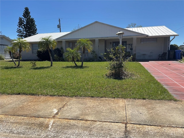 ranch-style home with metal roof, brick siding, a front lawn, and a standing seam roof