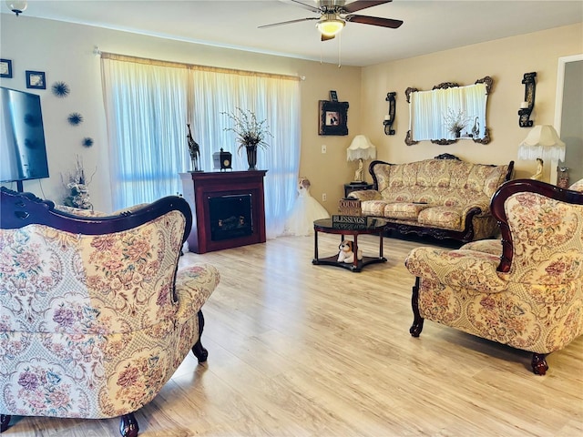 living room with a fireplace, wood finished floors, and a ceiling fan