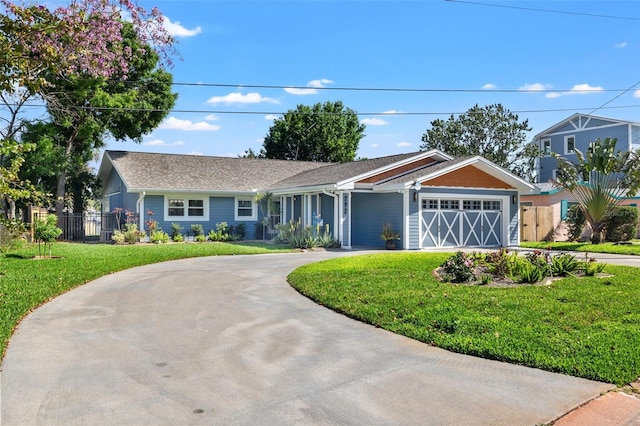 ranch-style home with fence, a front yard, a garage, and curved driveway