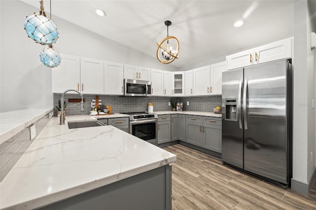 kitchen with gray cabinets, tasteful backsplash, a sink, and stainless steel appliances
