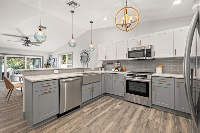 kitchen with a sink, gray cabinets, appliances with stainless steel finishes, and a peninsula