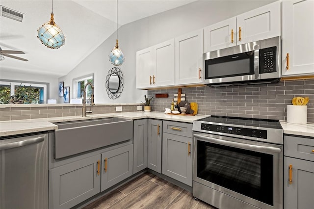 kitchen with gray cabinets, backsplash, a sink, stainless steel appliances, and visible vents