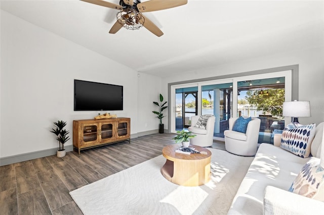 living room featuring baseboards, ceiling fan, wood finished floors, and vaulted ceiling