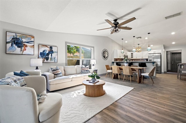 living room with lofted ceiling, visible vents, a ceiling fan, and wood finished floors