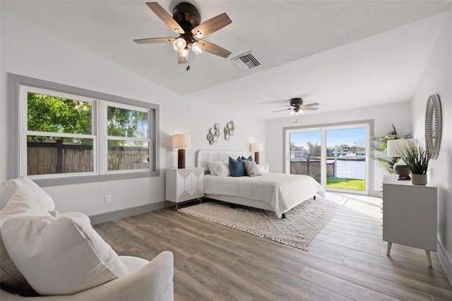 bedroom featuring access to exterior, visible vents, wood finished floors, and a textured ceiling