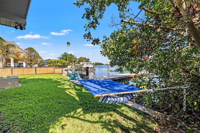 view of yard with a water view, fence, and a boat dock