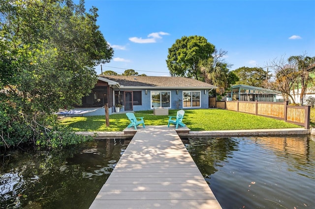 view of dock featuring a water view, fence, and a lawn