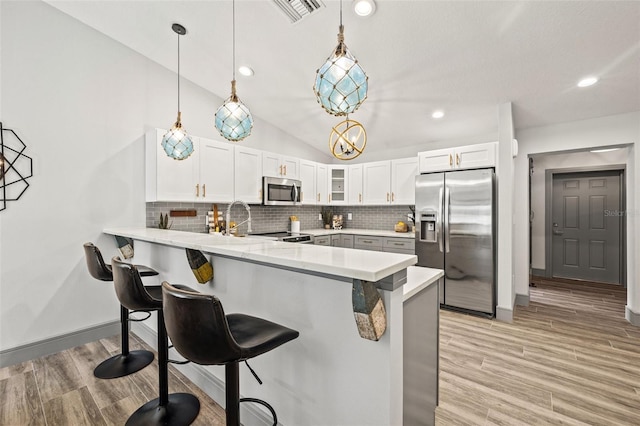 kitchen with visible vents, a peninsula, a kitchen bar, stainless steel appliances, and tasteful backsplash