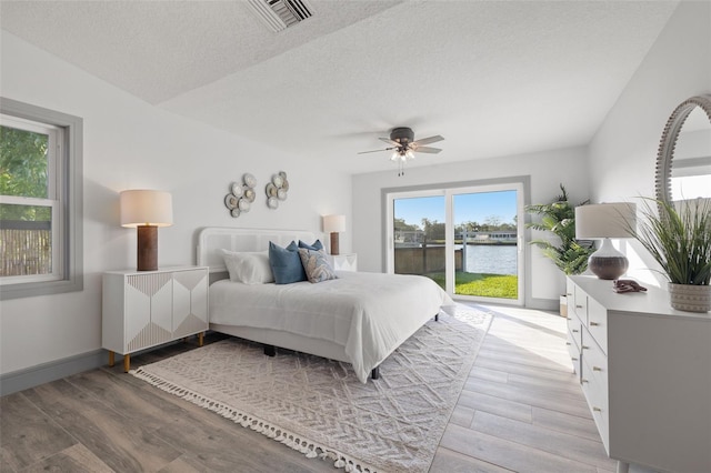 bedroom featuring a textured ceiling, visible vents, access to exterior, light wood-type flooring, and radiator