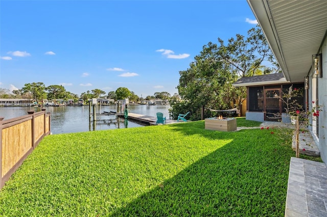 view of yard with a sunroom, boat lift, a water view, and a dock