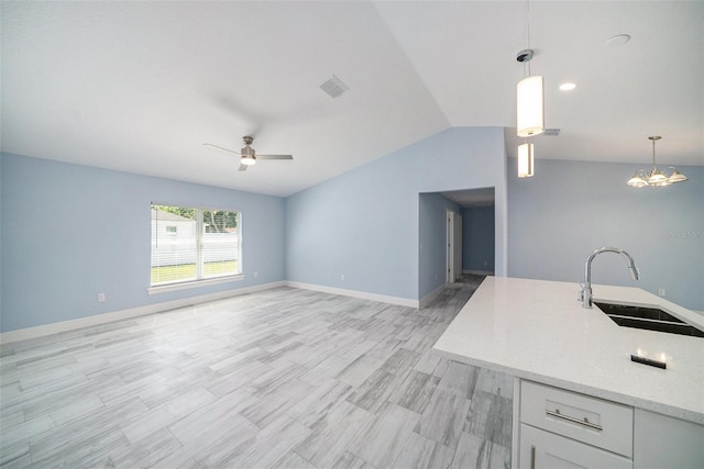 unfurnished living room featuring vaulted ceiling, a sink, ceiling fan with notable chandelier, baseboards, and visible vents