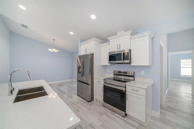 kitchen with a sink, stainless steel appliances, baseboards, a notable chandelier, and visible vents