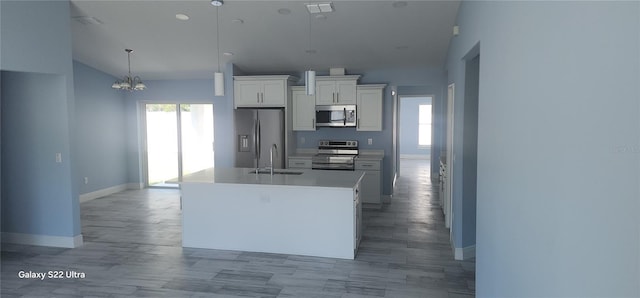 kitchen featuring vaulted ceiling, a sink, baseboards, appliances with stainless steel finishes, and white cabinetry