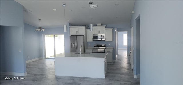 kitchen featuring white cabinets, a sink, vaulted ceiling, baseboards, and appliances with stainless steel finishes