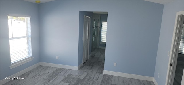unfurnished room featuring wood finished floors, baseboards, and a wealth of natural light
